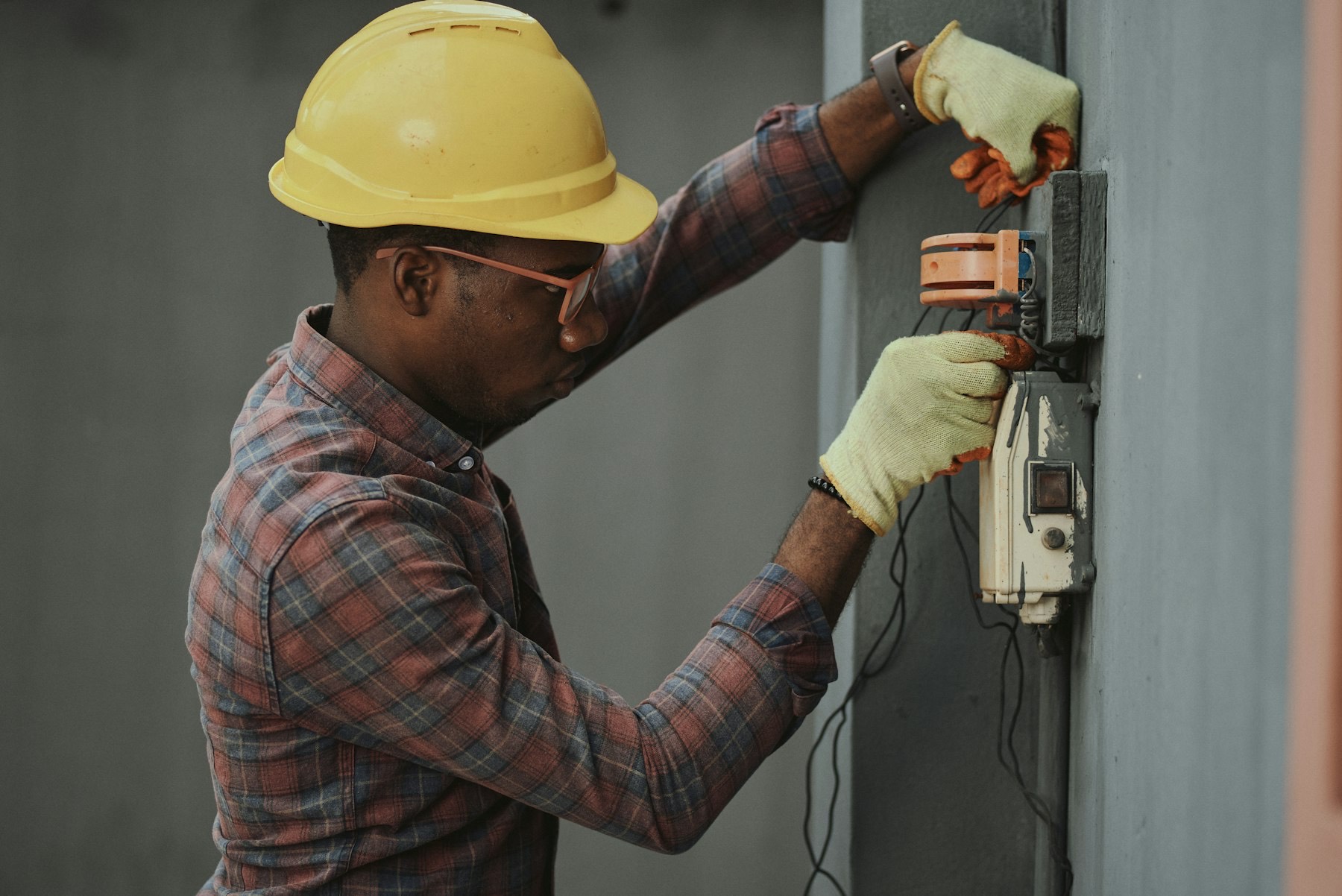 Electrician in a hard hat terminating a control unit on a wall panel